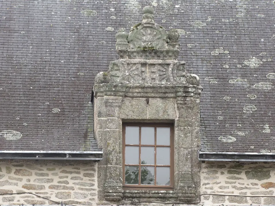 Lucarne en pierre sculptée sur un toit d'ardoise ancien, rue Victor-Robic au Faouët.